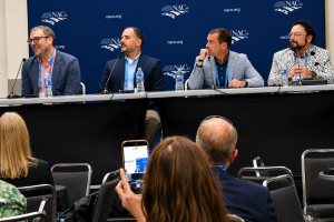 Four men sitting at table before conference